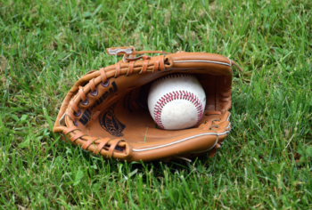 a baseball in a baseball glove, lying on the grass