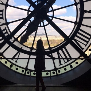 figure standing in front of a huge clock with a window in the middle, Musee D'Orsay #Notre Dame Before The Fire