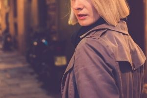 blonde woman in a raincoat on the street at night