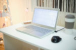 computer in front of window, coffee, holiday lights in background