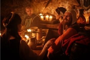 medieval lords and ladies having an evening meal by candlelight