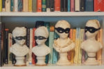 plaster busts wearing masks as bookshelf decor