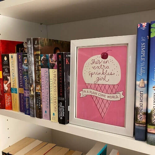 framed greeting card with an ice cream design that reads, "She's an extra sprinkles girl in an ice cream world." on bookshelves