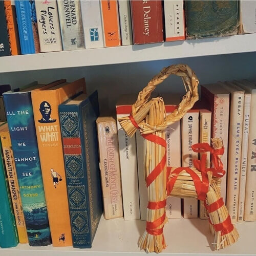 Swedish straw goat holiday decoration on bookshelves