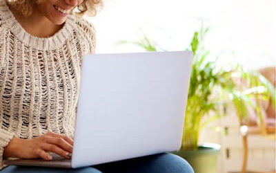 woman smiling and writing on laptop
