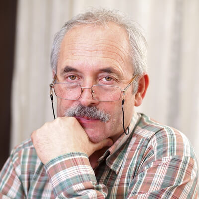 older white man staring over his glasses with annoyed expression