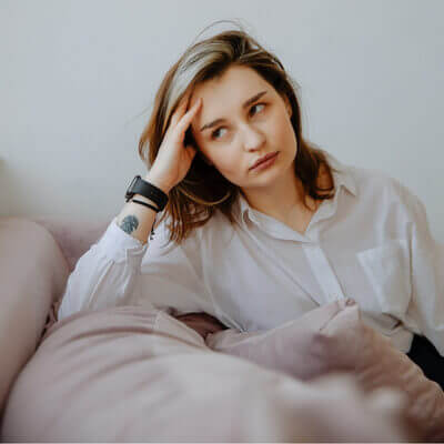 white woman with annoyed expression, looking away, hand on head