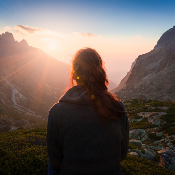 woman looking at sunrise and thinking about her life goals list