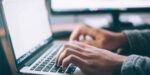 woman's hands writing on laptop