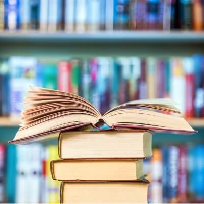 stack of books with bookshelves in background