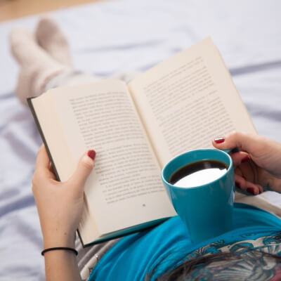 woman reading a book with mug in hand about why reading is important