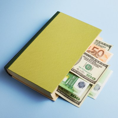 book with blank cover and lots of 50 and 100 dollar bills tucked inside