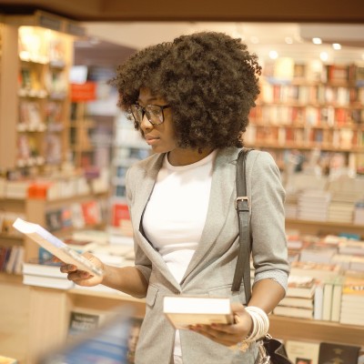 woman in a bookstore looking at a book cover