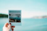 woman's hand holding up polaroid in front of landscape