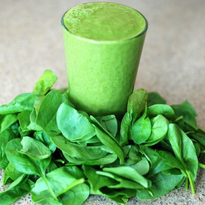 green smoothie surrounded by spinach