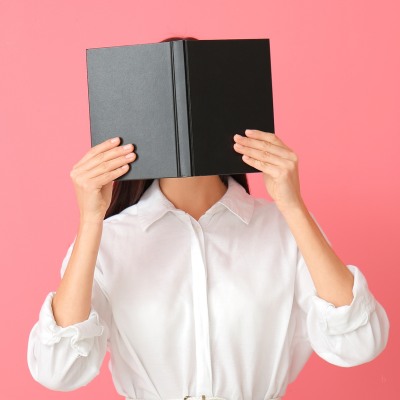 woman hiding face behind book, representing fear of ageism